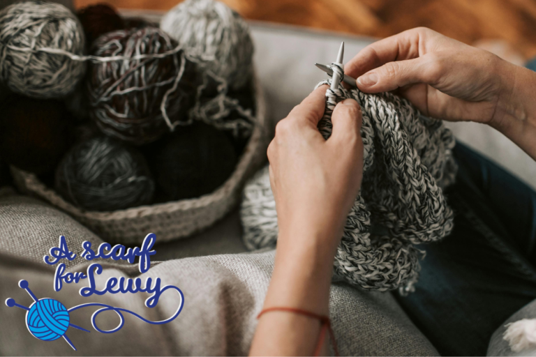 Woman's hands knitting with grey wool with Scarf for Lewy logo in blue on bottom left of picture