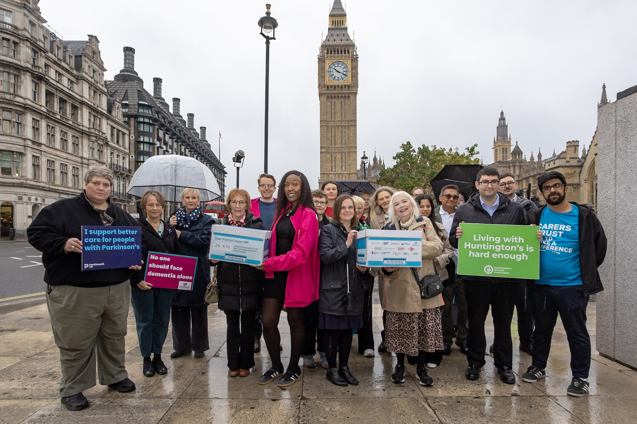 Group of people with boxes full of signatures outside the Houses of Parliament for the Continuing healthcare petition
